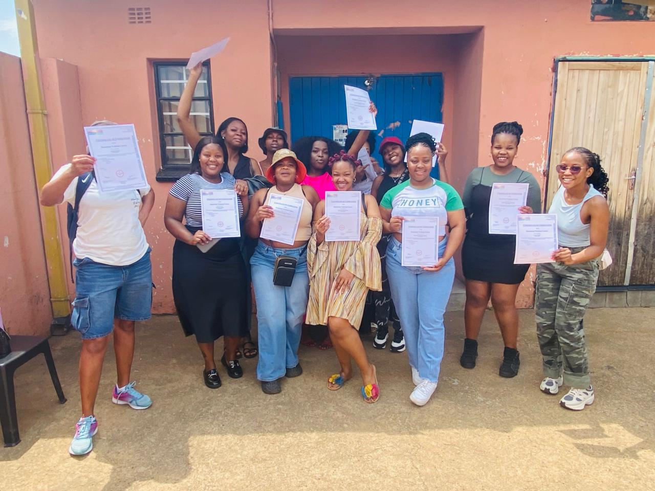 Beauty and nail care graduates holding their certificates outside the centre